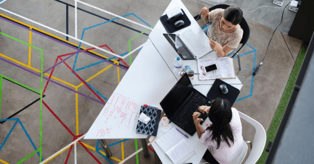 A photo from above with two women working together from two laptops